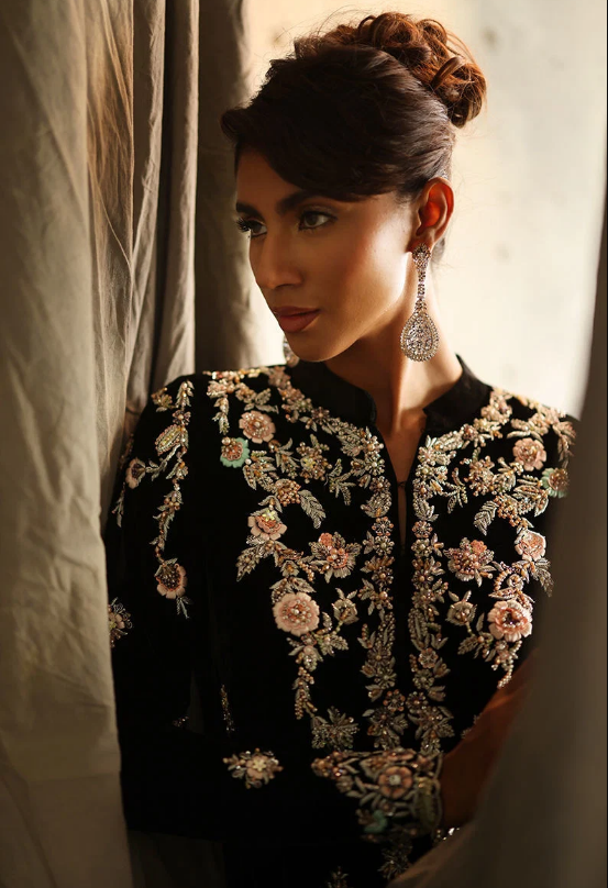 Woman wearing black velvet embroidered suit with floral detailing, front view full length