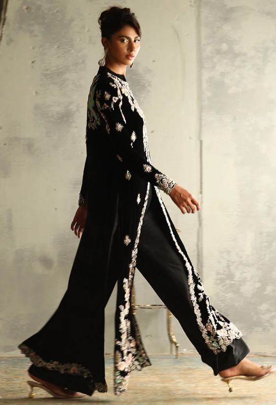 Woman wearing black velvet embroidered suit with floral detailing, front view full length