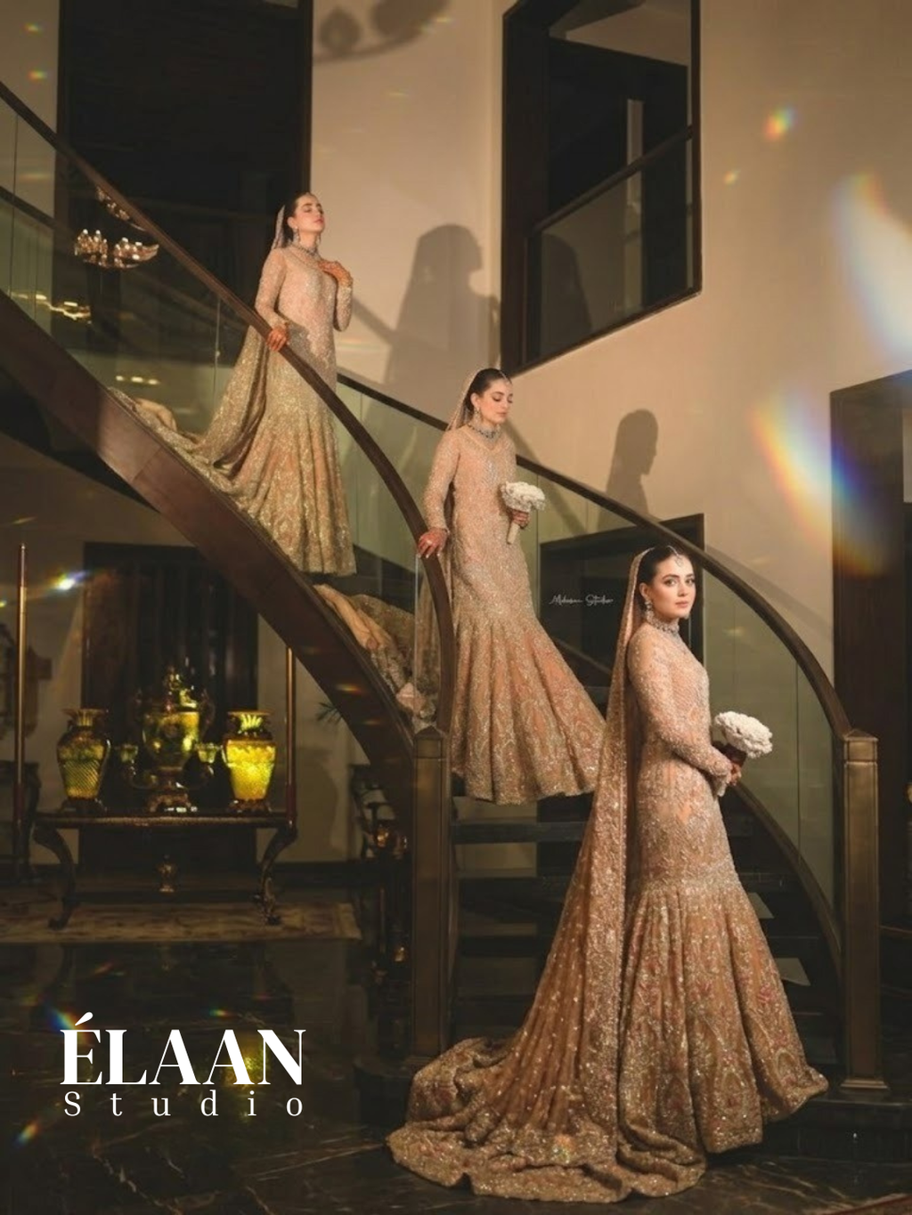 Bride wearing rose gold fully embellished fishtail bridal gown with dramatic train on staircase, holding bouquet - Èlaan Studio wedding wear