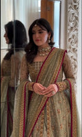 Bride wearing olive green embellished lehenga with maroon bordered dupatta, standing in front of ornate mirror - Èlaan Studio bridal wear