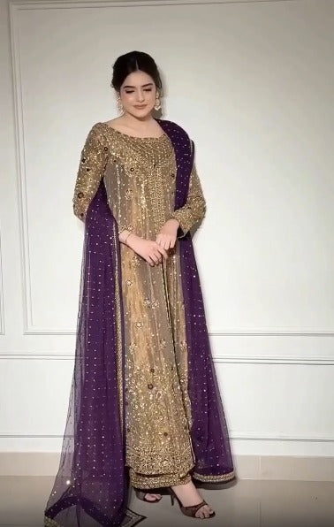 Model in gold embellished suit with purple dupatta standing against wall paneling - Èlaan Studio formal wear