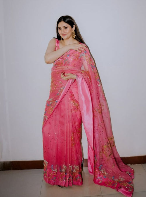 Model wearing pink organza saree with scattered sequin floral embroidery, standing against plain wall - Èlaan Studio party wear