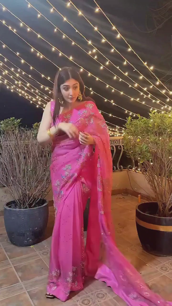 Model wearing pink organza saree with scattered sequin floral embroidery, standing against plain wall - Èlaan Studio party wear