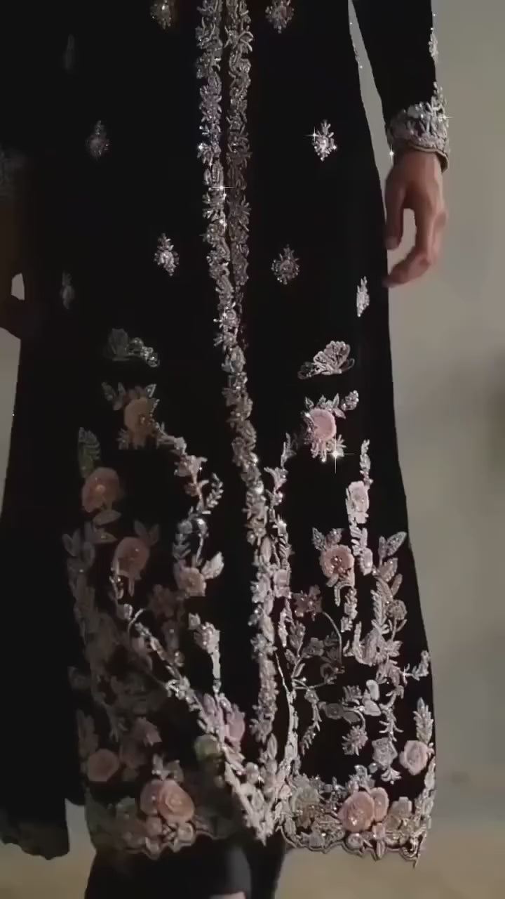 Woman wearing black velvet embroidered suit with floral detailing, front view full length